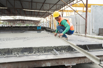 Fototapeta na wymiar Construction technician working by leveling concrete floor to smooth. Construction worker uses long trowel spreading wet concrete pouring at construction site. Mason making smooth surface of concrete
