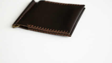 Empty brown men's money clip handmade leather wallet with a two pockets for cards lies on a white table. Selective focus, copy space, close up.