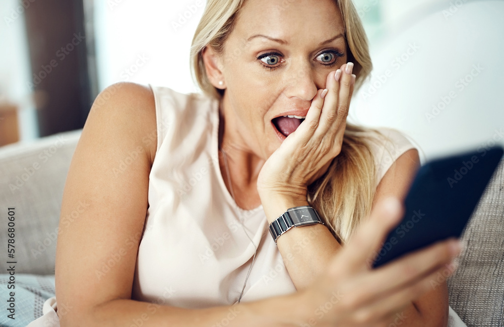Poster whaaat. an attractive mature woman looking surprised while reading a text message at home.