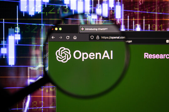 OpenAI chatbot company logo on a website with blurry stock market developments in the background, seen on a computer screen through a magnifying glass