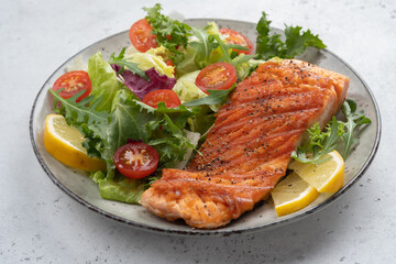 Grilled salmon fish fillet and fresh green lettuce vegetable tomato salad