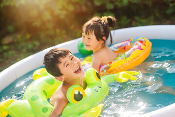 Family vacation in an inflatable pool in summer. Children swim on inflatable circles. - obrazy, fototapety, plakaty