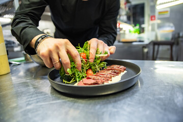 chef hand preparing Roastbeef salad with vegetables on restaurant kitchen