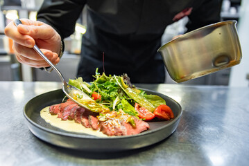 chef hand preparing Roastbeef salad with vegetables on restaurant kitchen