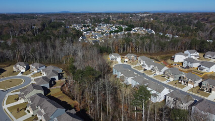 Obraz premium Planned settlement suburban area with Chestnut Mountain background and row of new developments houses, traffic circle (roundabout), cul-de-sac, lush green trees, Georgia, US