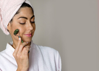 Beautiful woman using green jade roller for face massage . Daily Jade Roller Facial Massage Routine
