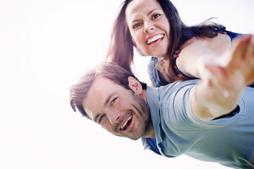 Your love makes me fly high. A handsome man piggybacking his loving wife outdoors.