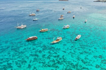 Paradisiacal panoramic bird's eye view of turquoise blue sea in Komodo National Park on Flores with countless boats.