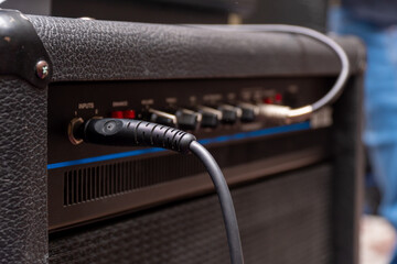Plug jack with cable plugged into a black guitar combo amplifier