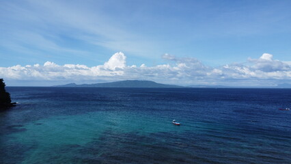 Aerial view of the sea surface and clouds. Small boat in the lagoon.