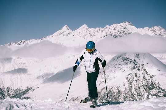 skier at ski resort standing on sunny day against backdrop of beautiful mountain peaks in the clouds