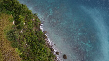 Aerial view of the coastline of an island covered in jungle.