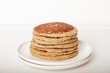 Delicious freshly cooked thick and fluffy protein pancakes stacked on white plate. Healthy food, low carb diet.