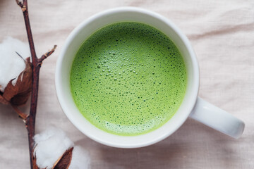 Cup of freshly made delicious matcha tea on neutral beige background. View from above. Morning hot drink.