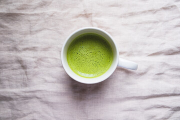 Cup of freshly made delicious matcha tea on neutral beige background. View from above. Morning hot drink.