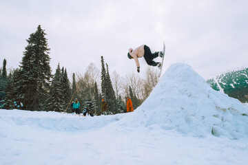 Naklejka na ściany i meble Snowboarder female jumping from kicker in winter sunny day