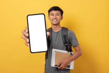 Smiling young college student with books and backpack isolated on yellow background showing big smartphone with white blank screen in hand. Advertisement special offer Concept.