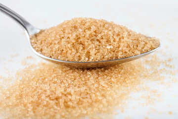 Brown sugar in silver spoon on white background