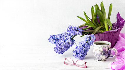 A still life of purple Hyacinth flower blooms with a cup of coffee in front.