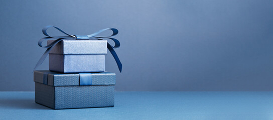 Two Luxury gift boxes with a blue bow on dark blue. Side view monochrome . Fathers day or...