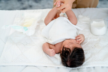 Close up view mother change diaper or napkin for newborn baby lie on white bed after she excrete...