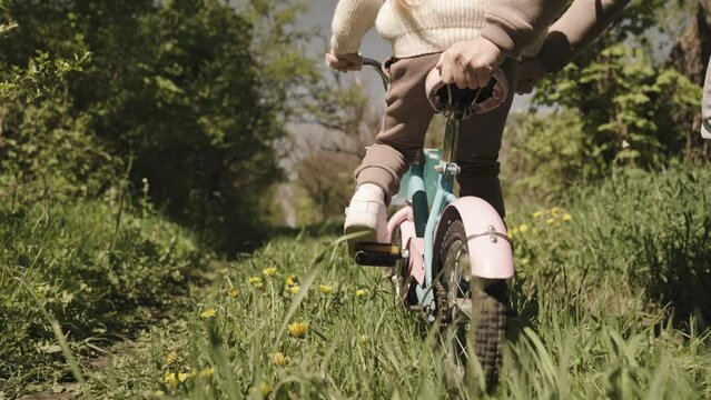 mother rides child two-wheeled bicycle park. happy family concept. mom child outdoors. childhood dream child. girl daughter with mom walk with bike forest. family walk nature. happy family teamwork