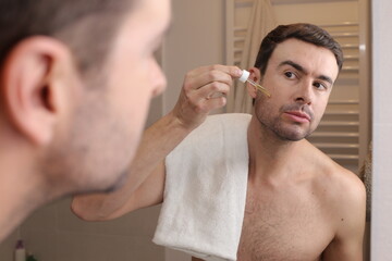 Fototapeta premium Man applying serum drops in the bathroom 