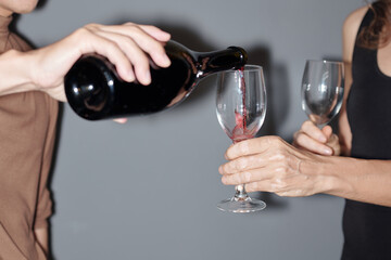 Young man filling glass of girlfriend with red wine