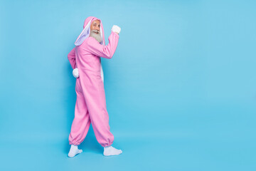 Side profile full size photo of cheerful elderly pensioner wear pink bunny costume demonstrating...