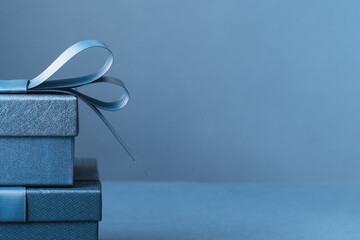 Two Luxury gift boxes with a blue bow on dark blue. Side view monochrome . Fathers day or...