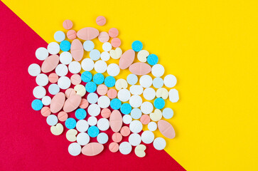 The colorful medicine tablets on yellow and red color background.