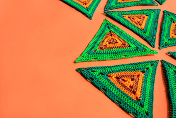 Right side is filled with big crochet triangles of green and orange color, left side is free, the...