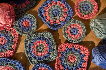 Top view of granny squares with skeins of cotton on wooden surfa
