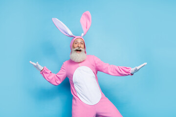Photo of positive charming man pensioner dressed pink rabbit nightwear dancing smiling isolated...