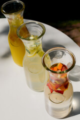 Summer lemonade c with fruit. Drink on a white table in the sunlight . Summer, tropical, fresh cocktail concept.