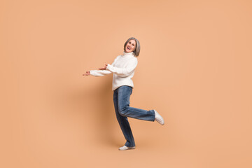 Fototapeta na wymiar Full length photo of excited funny woman wear knitted pullover showing arms empty space isolated beige color background