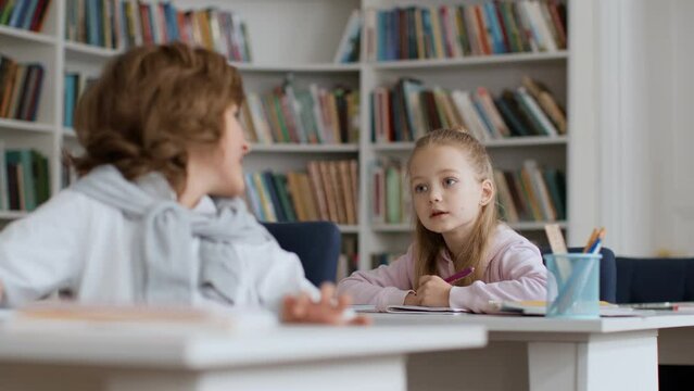 Cheating at school. Little boy can't remember test answer, turning to classmate for help, girl showing right answers
