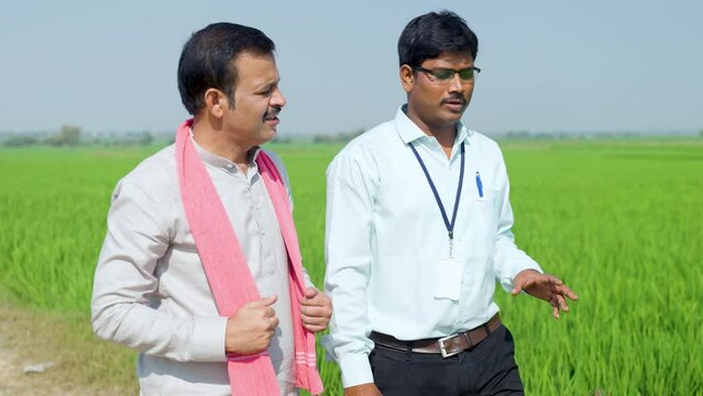 Tracking shot of banking officer with Village farmer discussing by looking around farmland - concept of information collection, agribusiness investment and supportive communication
