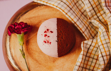 Whoopi pie cake on a round plate top view. A red carnation flower adorns a still life with a traditional American cookie. Round trendy details on a food photo Soft cookies with a creamy layer of flat - Powered by Adobe