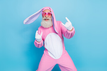 Photo of excited cool retired guy wear pink hare sleepwear heart glasses showing hard rock signs isolated blue color background