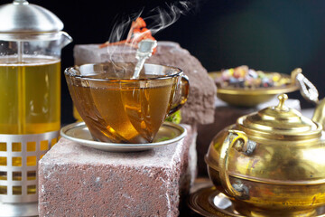 Sweet, hot tea with dry tea leaves, on an old background.