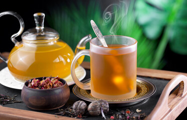 Sweet, hot tea with dry tea leaves, on an old background.