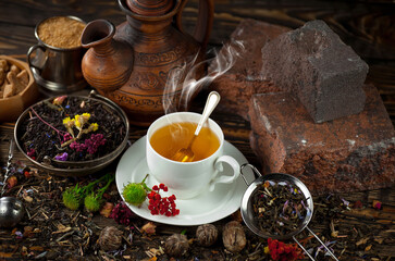 Sweet, hot tea with dry tea leaves, on an old background.