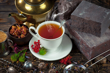 Sweet, hot tea with dry tea leaves, on an old background.