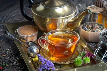 Fototapeten Sweet, hot tea with dry tea leaves, on an old background. © Karnav