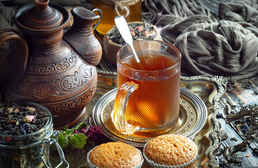 Sweet, hot tea with dry tea leaves, on an old background.