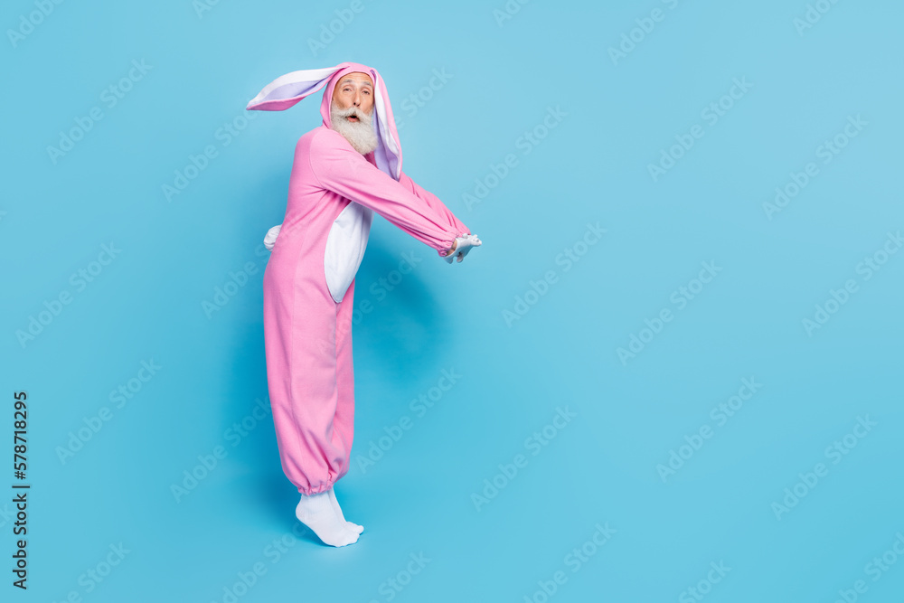 Sticker Full length photo of shocked charming pensioner guy dressed bunny kigurumi jumping empty space isolated blue color background