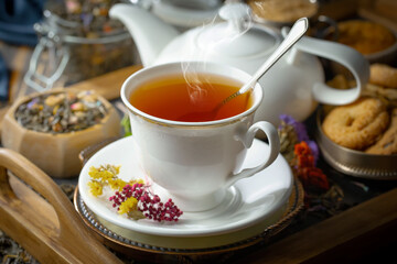 Sweet, hot tea with dry tea leaves, on an old background.