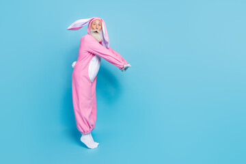 Full length photo of shocked charming pensioner guy dressed bunny kigurumi jumping empty space isolated blue color background
