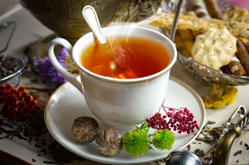 Sweet, hot tea with dry tea leaves, on an old background.